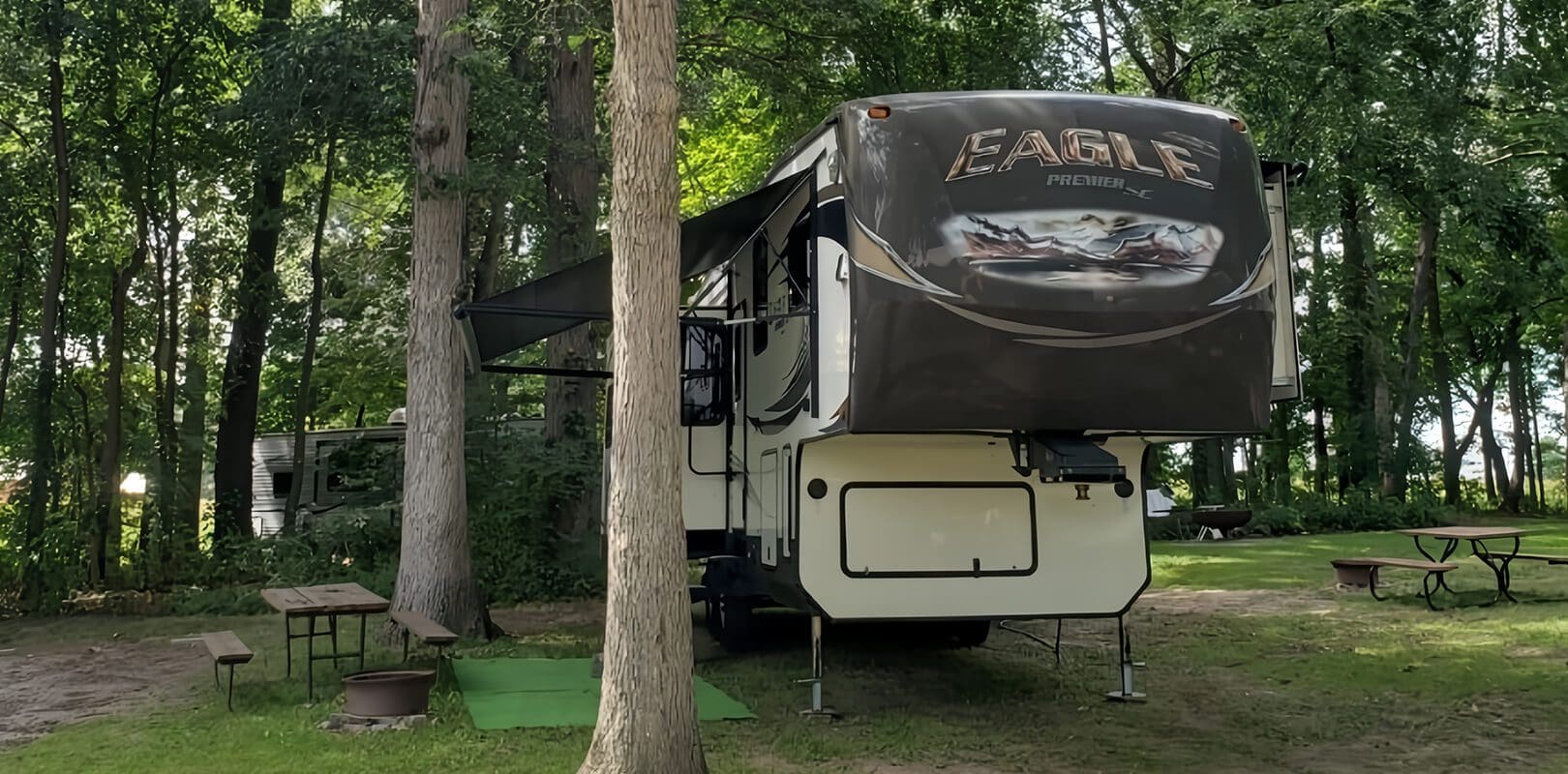 A large rv at a rv site in the woods near some trees at Gotta Getaway RV Park