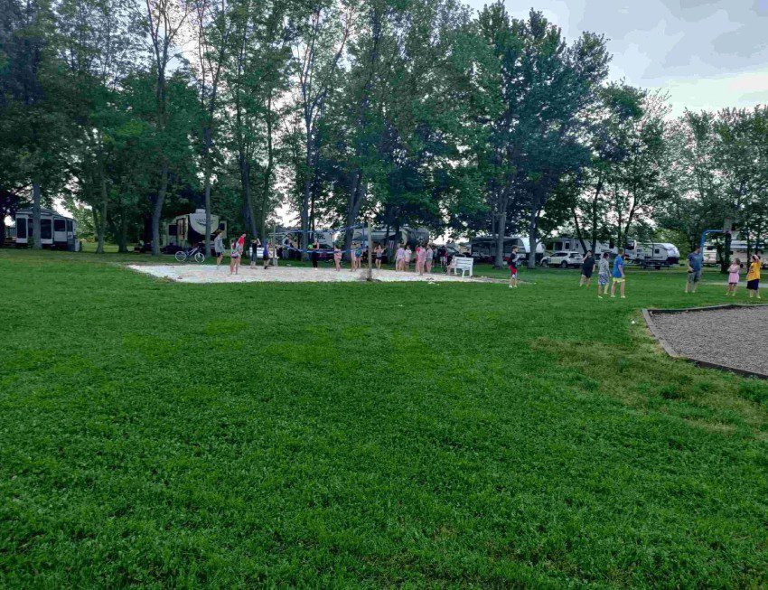 Volleyball Court, grassy area with trees and RV Sites in the background.