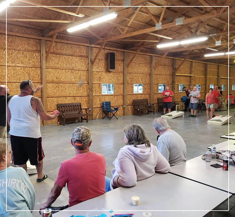 A group of people playing cornhole indoors at Gotta Getaway RV Park