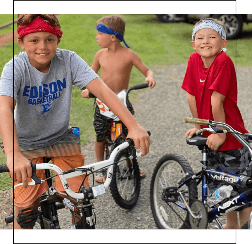 Three young boys riding bikes on a path.